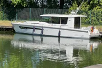 2024 Nimbus Commuter 11 boat docked on calm water, surrounded by greenery.