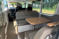 2024 Nimbus Commuter 11 interior with seating and table, featuring modern design and large windows.