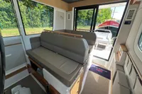 Interior of 2024 Nimbus Commuter 11 boat with seating and large windows.