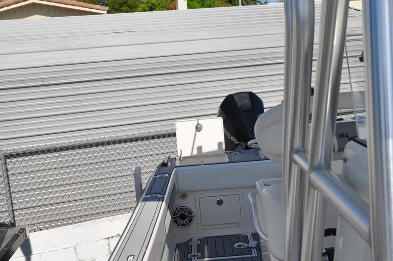  Yacht Photos Pics 2020 SeaVee 290B boat interior with seating and engine, parked near a metal fence.