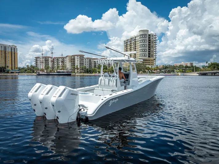 Yacht Photos Pics 2025 Yellowfin 36 boat with triple engines on a calm waterfront, cityscape in background.