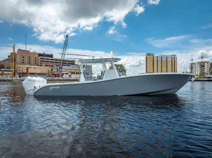  Yacht Photos Pics 2025 Yellowfin 36 boat on water, urban skyline background, partly cloudy sky.