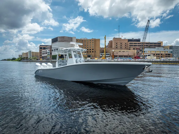  Yacht Photos Pics 2025 Yellowfin 36 boat on water, urban backdrop, partly cloudy sky.