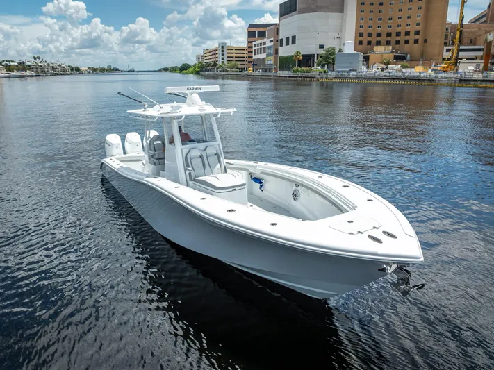  Yacht Photos Pics 2025 Yellowfin 36 boat on a calm urban waterway under a partly cloudy sky.