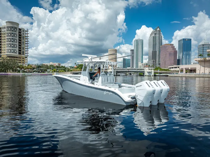  Yacht Photos Pics 2025 Yellowfin 36 boat on water with city skyline and cloudy sky background.