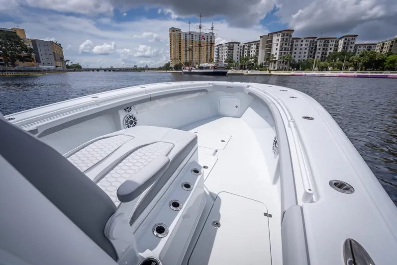  Yacht Photos Pics 2025 Yellowfin 36 boat on calm water, cityscape background, cloudy sky.