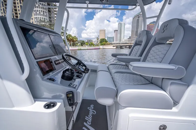  Yacht Photos Pics 2025 Yellowfin 36 boat interior with modern dashboard and luxurious seating, city skyline in background.