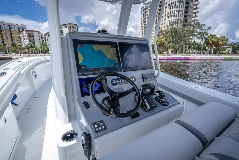  Yacht Photos Pics 2025 Yellowfin 36 boat cockpit with advanced navigation system and steering wheel, docked by waterfront buildings.