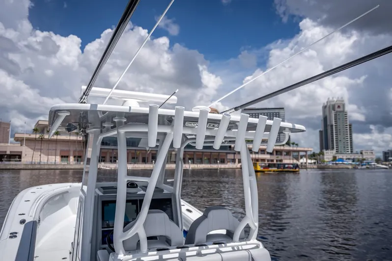  Yacht Photos Pics 2025 Yellowfin 36 boat on water with cityscape background, under cloudy sky.