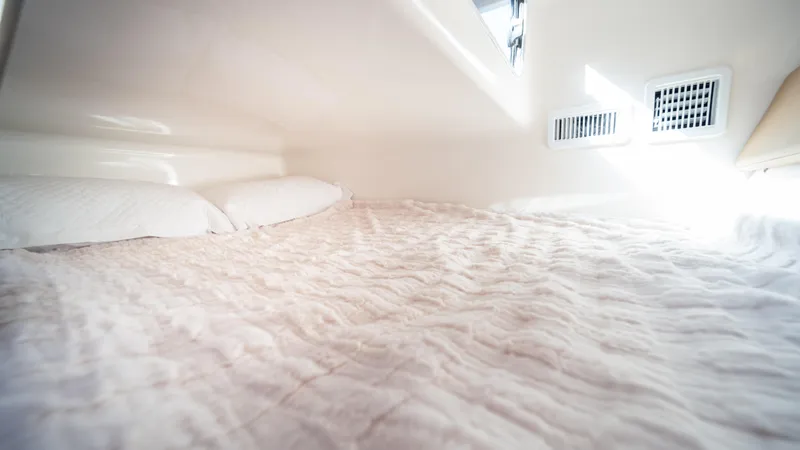  Yacht Photos Pics Cozy bed in 2025 Hanover 305 boat cabin with soft lighting.