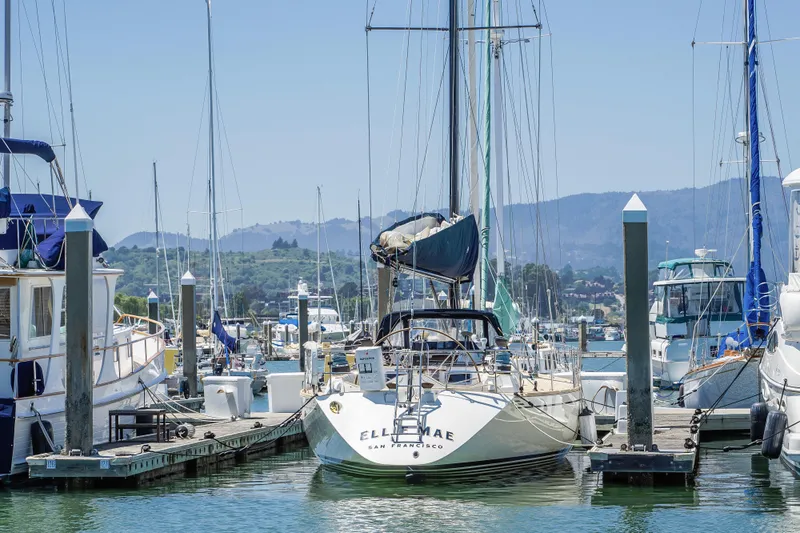 Hasard III Yacht Photos Pics Baltic 48 DP 1986 sailboat docked at a marina with mountains in the background.