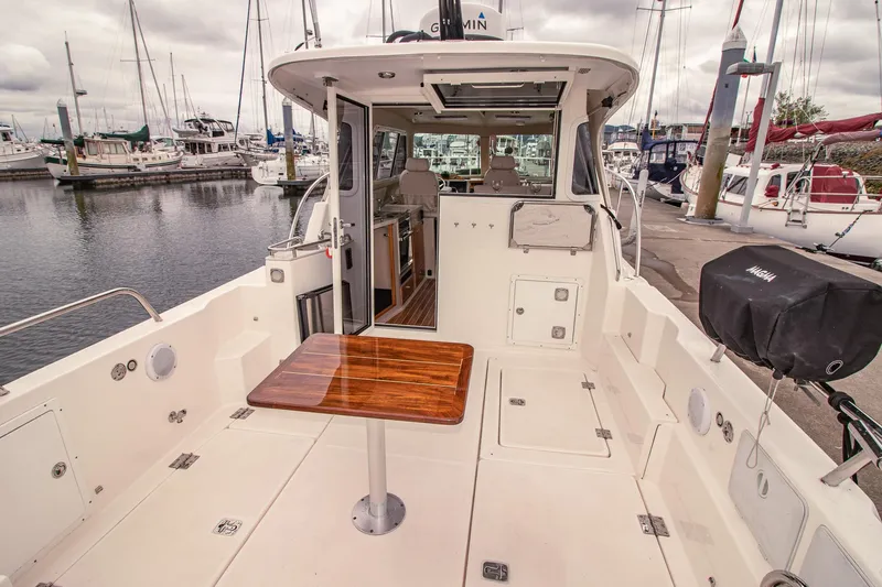 Halcyon Yacht Photos Pics Aspen C100 boat interior with wooden table, docked at marina, cloudy sky.