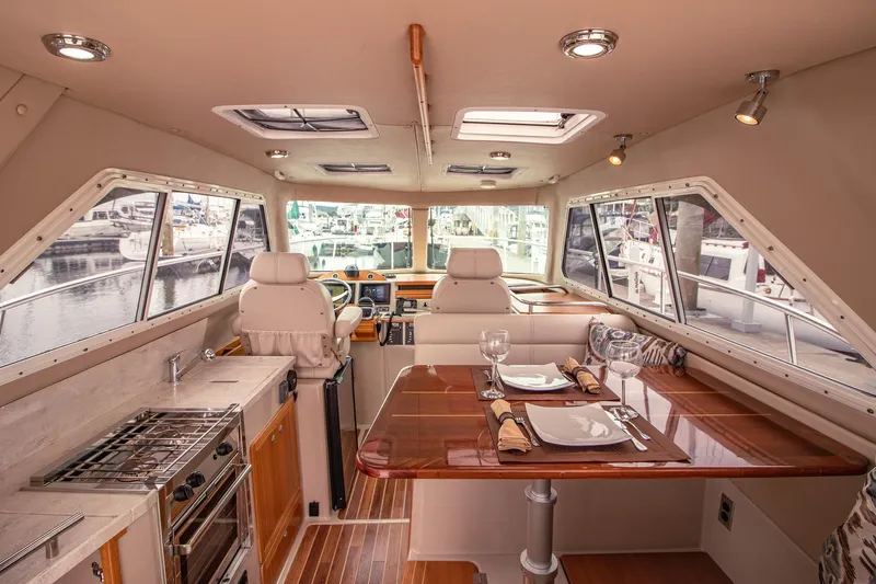 Halcyon Yacht Photos Pics Luxurious interior of 2015 Aspen C100 boat with dining area and helm, docked at marina.