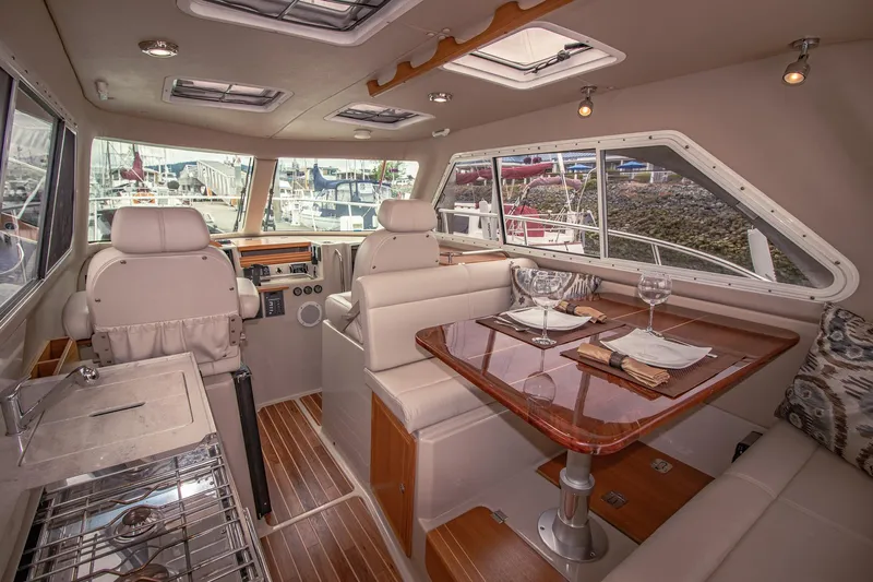 Halcyon Yacht Photos Pics Luxurious interior of 2015 Aspen C100 boat with dining area and helm, docked at marina.