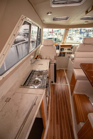 Halcyon Yacht Photos Pics Interior of 2015 Aspen C100 boat with kitchen and seating area, featuring wood flooring.