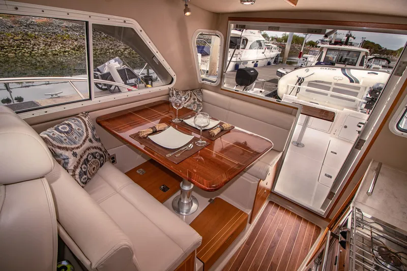 Halcyon Yacht Photos Pics Luxurious interior of 2015 Aspen C100 boat with elegant dining area and scenic marina view.