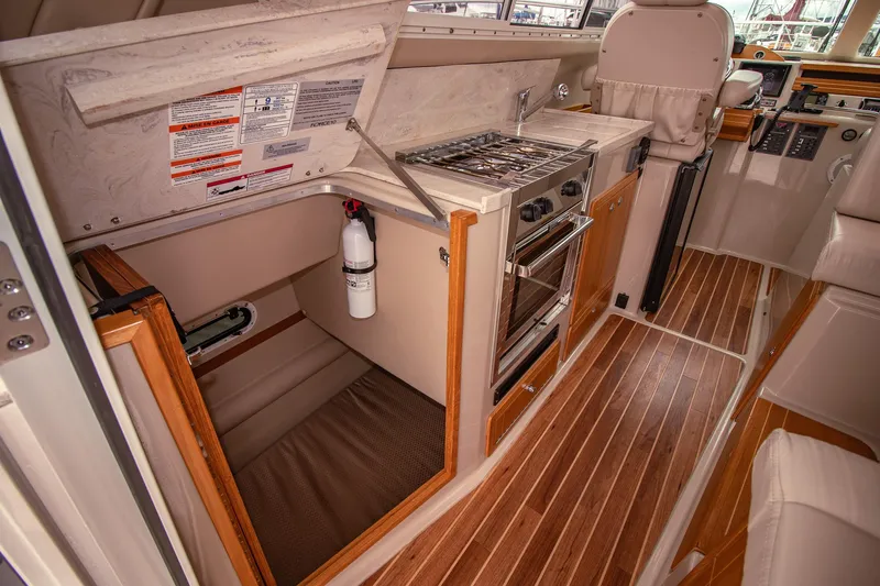 Halcyon Yacht Photos Pics Interior of 2015 Aspen C100 boat featuring kitchen area with stove and wooden flooring.