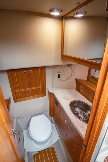 Halcyon Yacht Photos Pics Compact boat bathroom with wooden cabinetry, sink, and toilet in Aspen C100, 2015 model.