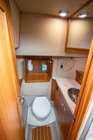 Halcyon Yacht Photos Pics Compact boat bathroom with wooden cabinetry, toilet, sink, and storage in a 2015 Aspen C100.