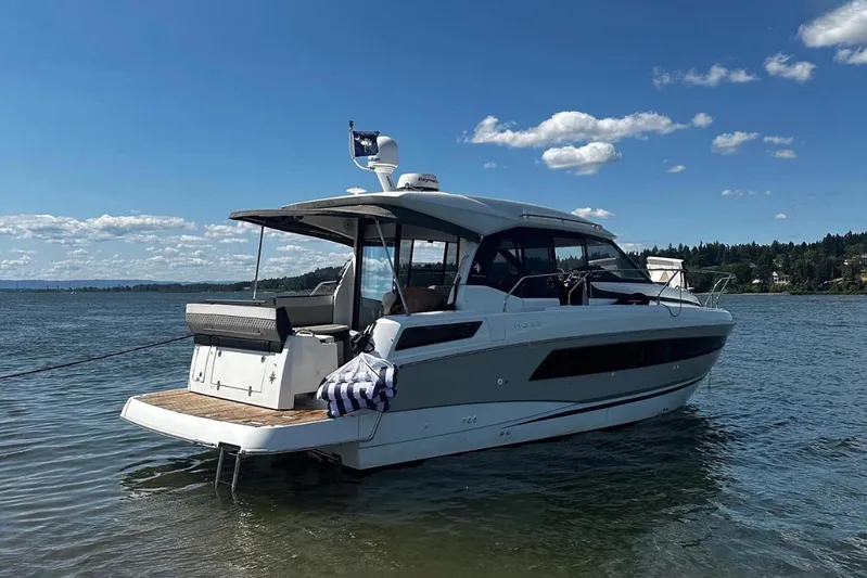  Yacht Photos Pics 2019 Jeanneau NC 33 yacht on calm water under a clear blue sky.