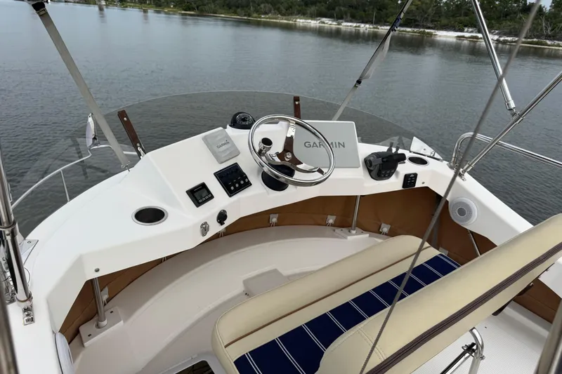  Yacht Photos Pics 2022 Ranger Tugs R-31 CB helm with Garmin navigation, steering wheel, and controls on calm water.