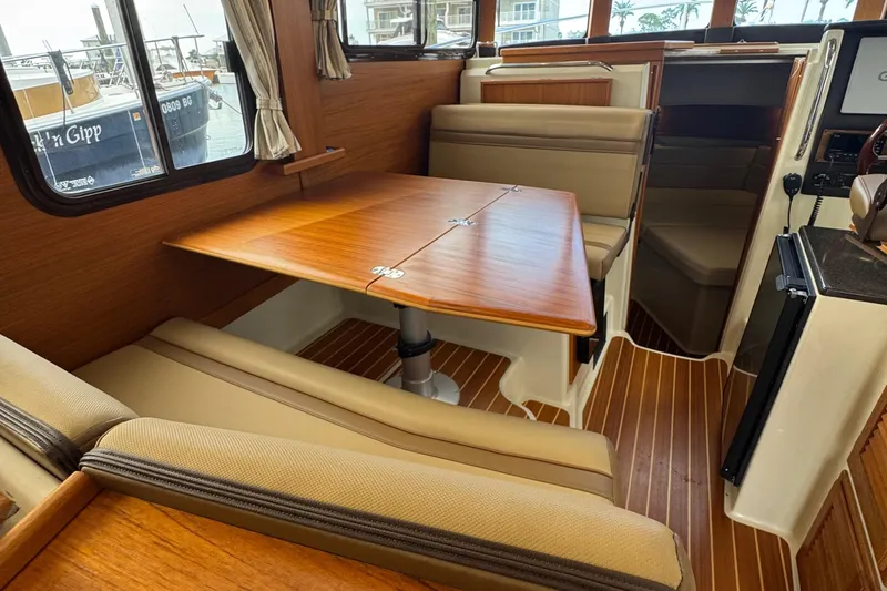  Yacht Photos Pics Interior of 2022 Ranger Tugs R-31 CB with wood table and beige seating.
