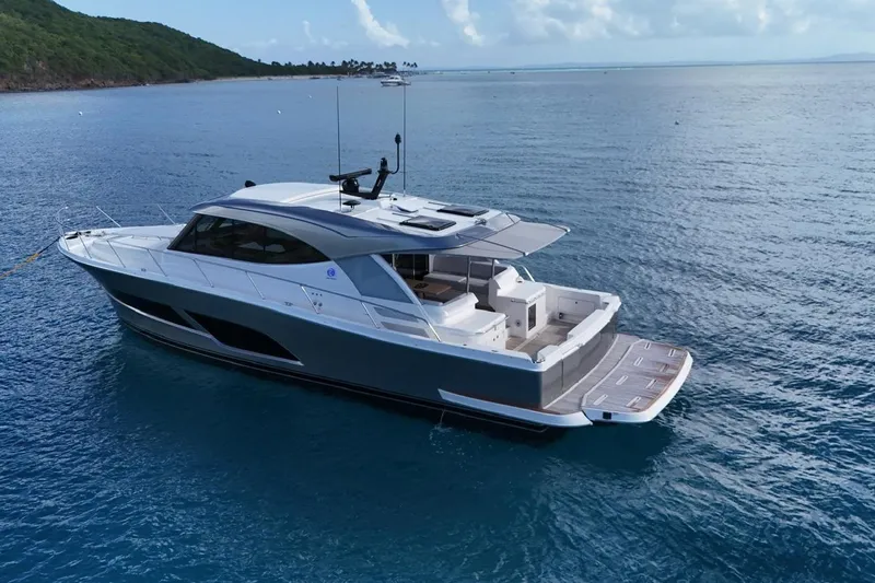  Yacht Photos Pics 2026 Riviera 505 SUV yacht on serene blue ocean near lush coastline.