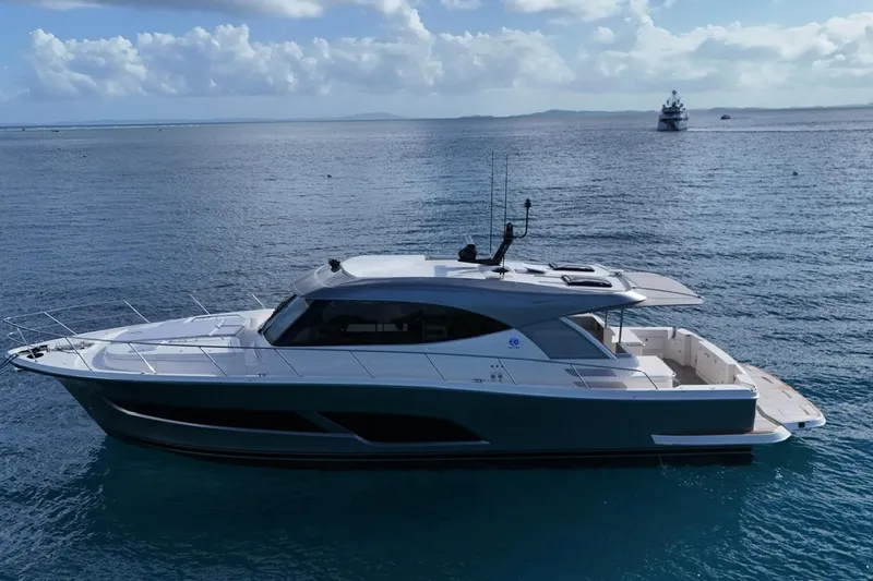  Yacht Photos Pics 2026 Riviera 505 SUV yacht cruising on calm ocean waters under a cloudy sky.