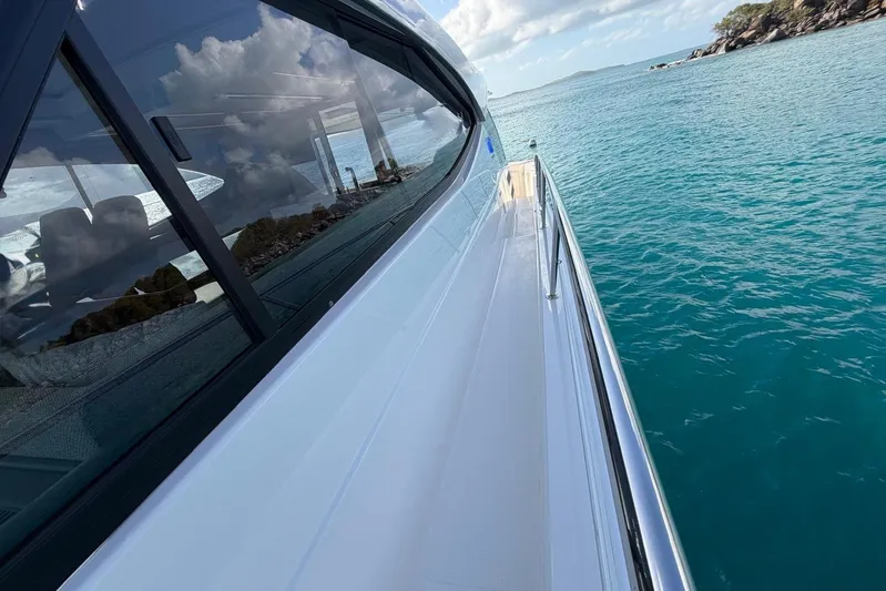  Yacht Photos Pics 2026 Riviera 505 SUV yacht cruising on clear blue waters under a partly cloudy sky.