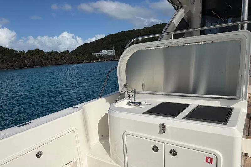  Yacht Photos Pics 2026 Riviera 505 SUV yacht with outdoor kitchenette, ocean view, and clear skies.