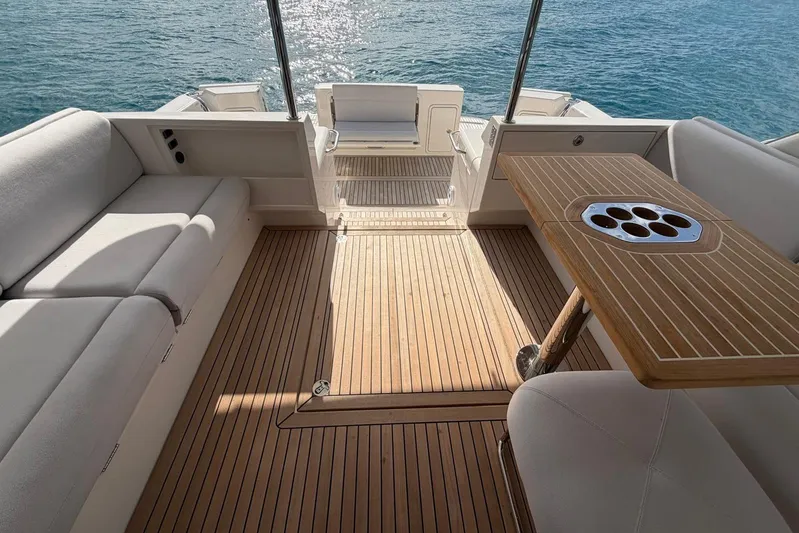  Yacht Photos Pics Luxurious 2026 Riviera 505 SUV yacht deck with elegant seating and wooden table, overlooking serene water.