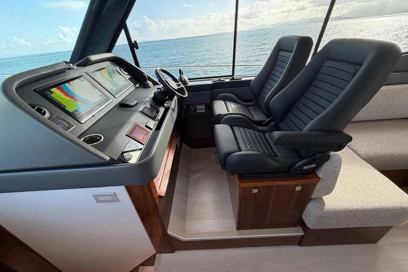  Yacht Photos Pics 2026 Riviera 505 SUV cockpit with dual seats and navigation screens, overlooking the ocean.