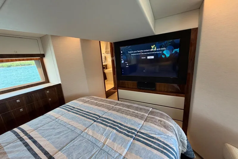  Yacht Photos Pics Luxurious bedroom interior of 2026 Riviera 505 SUV yacht with TV and scenic window view.