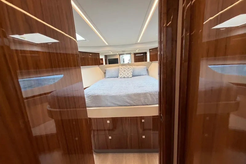  Yacht Photos Pics Luxurious bedroom interior of 2026 Riviera 505 SUV yacht with elegant wood finish.