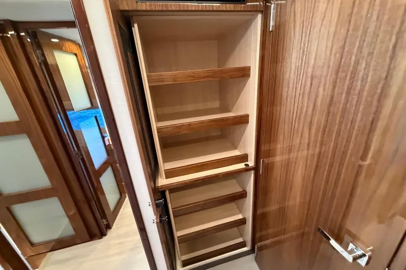  Yacht Photos Pics Wooden shelving inside 2026 Riviera 505 SUV yacht interior, showcasing elegant design.