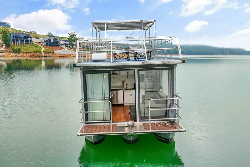  Yacht Photos Pics Modern 2024 Gospel 39 houseboat on serene lake with scenic hillside view.