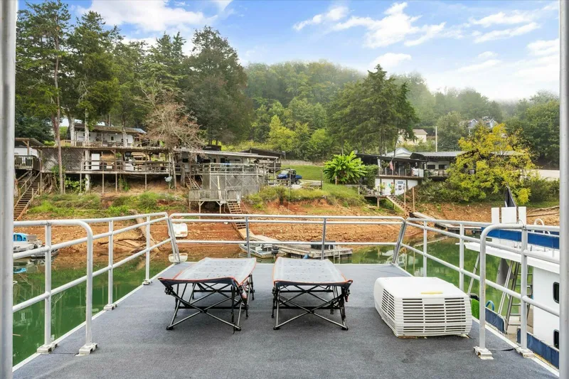  Yacht Photos Pics Deck view from 2024 Gospel 39 houseboat overlooking lakeside cabins and lush greenery.