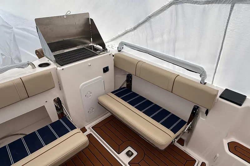  Yacht Photos Pics 2025 Ranger Tugs R-25 boat interior with seating and grill, featuring teak flooring.