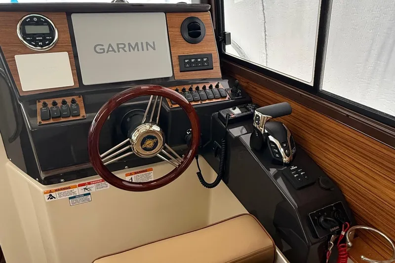  Yacht Photos Pics 2025 Ranger Tugs R-25 helm with Garmin navigation, wood accents, and modern controls.