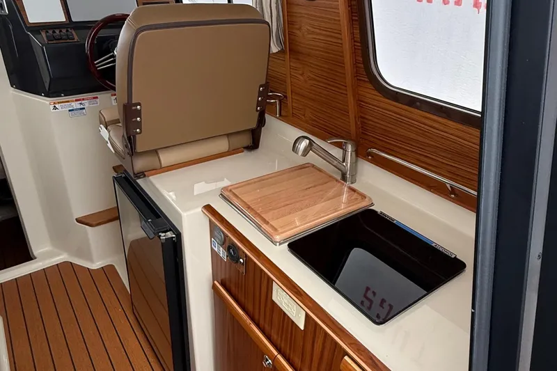  Yacht Photos Pics Interior of 2025 Ranger Tugs R-25, featuring helm, sink, and wooden cabinetry.