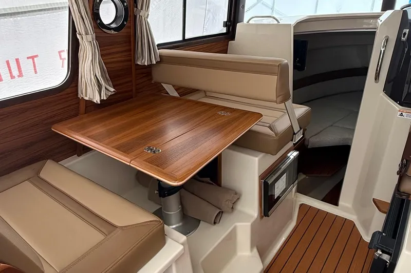  Yacht Photos Pics Interior of 2025 Ranger Tugs R-25, featuring a wooden table and beige seating.