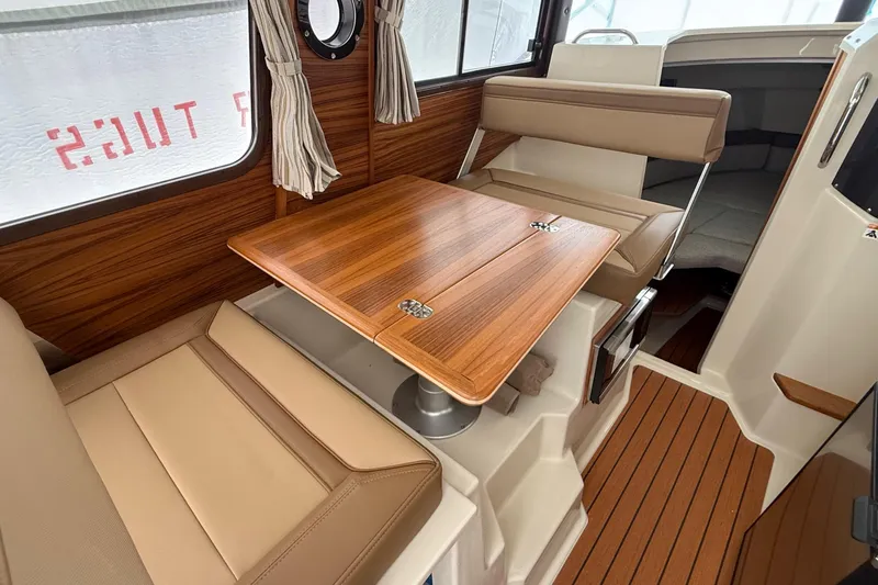  Yacht Photos Pics Interior of 2025 Ranger Tugs R-25, featuring a wooden table and beige seating.