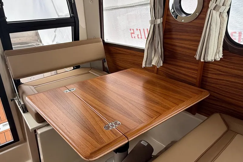  Yacht Photos Pics Interior of 2025 Ranger Tugs R-25 with wood table and beige seating.