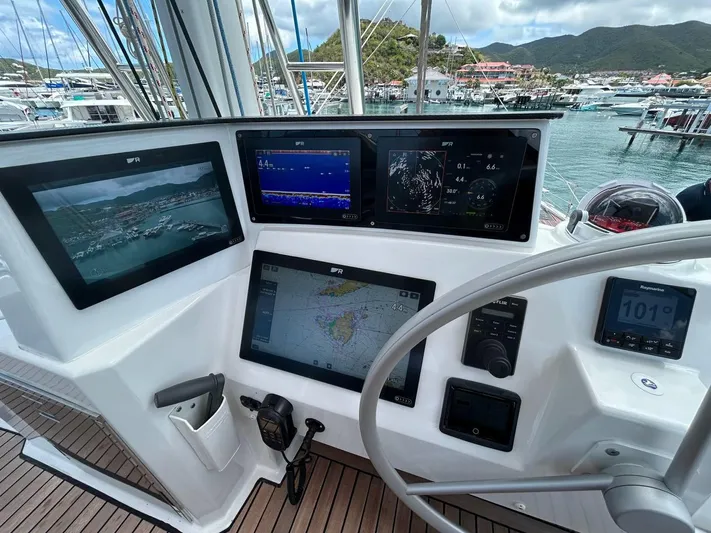 Voyager Yacht Photos Pics Cockpit of 2023 Bali 5.4 yacht with navigation screens and steering wheel in marina.