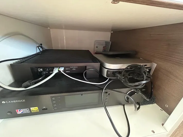 Voyager Yacht Photos Pics Audio equipment setup with cables and devices in a cabinet, featuring Cambridge and Roon Nucleus.