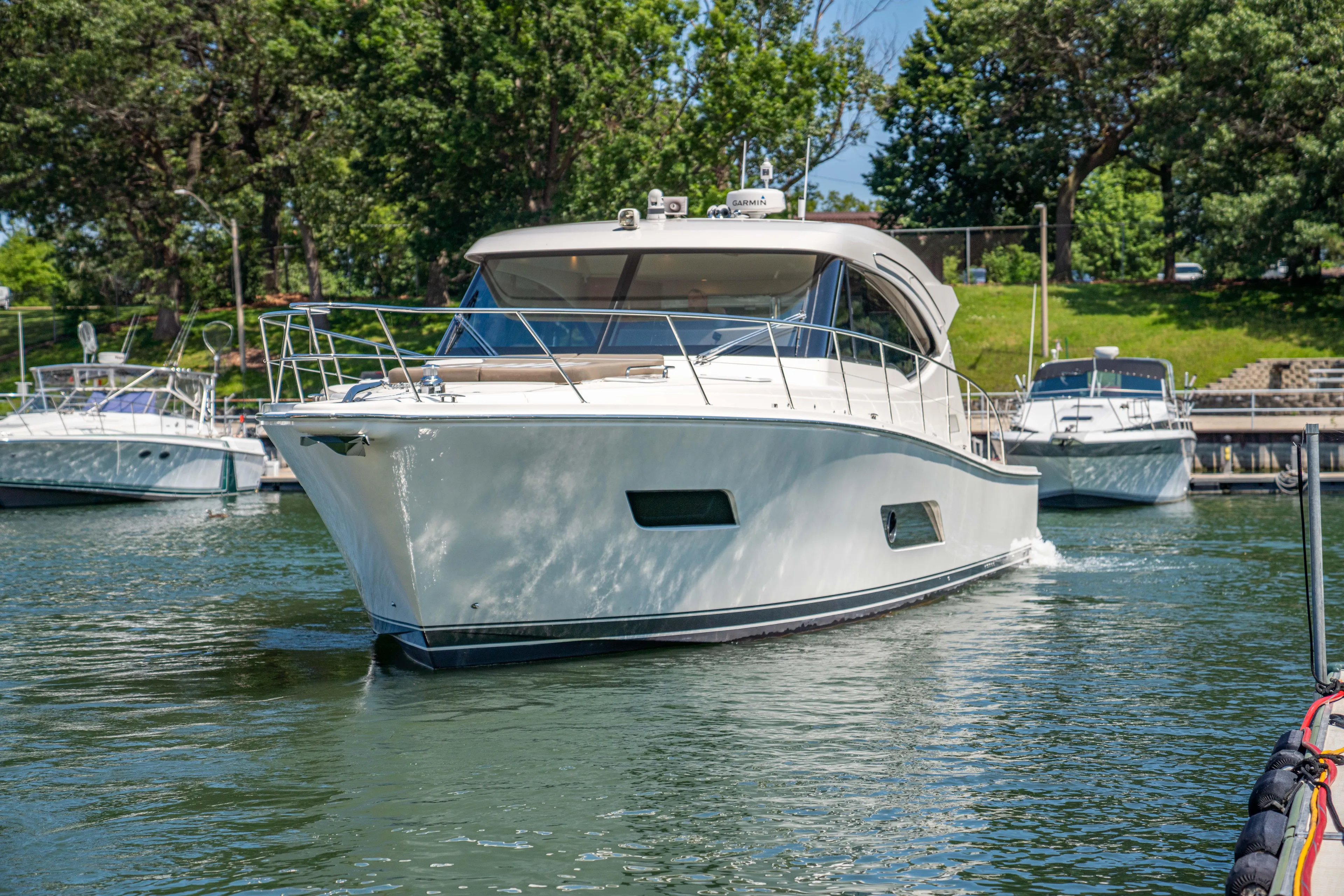  Yacht Photos Pics 2020 Riviera 525 SUV yacht cruising in a scenic marina setting.