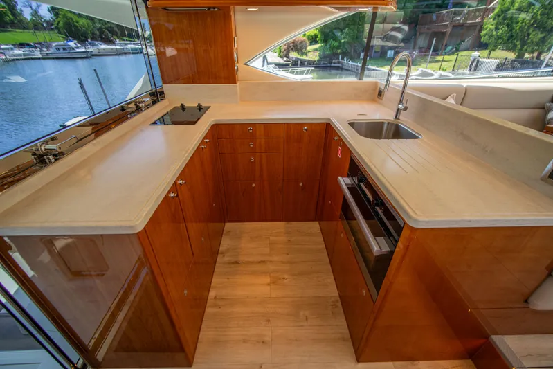  Yacht Photos Pics Luxurious 2020 Riviera 525 SUV yacht kitchen with modern wood cabinetry and waterfront view.