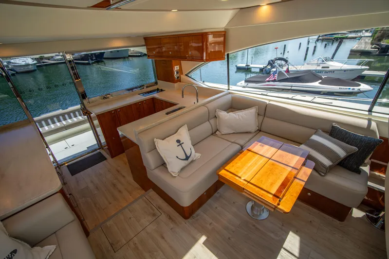  Yacht Photos Pics Luxurious 2020 Riviera 525 SUV interior with elegant seating and wooden table, docked at marina.