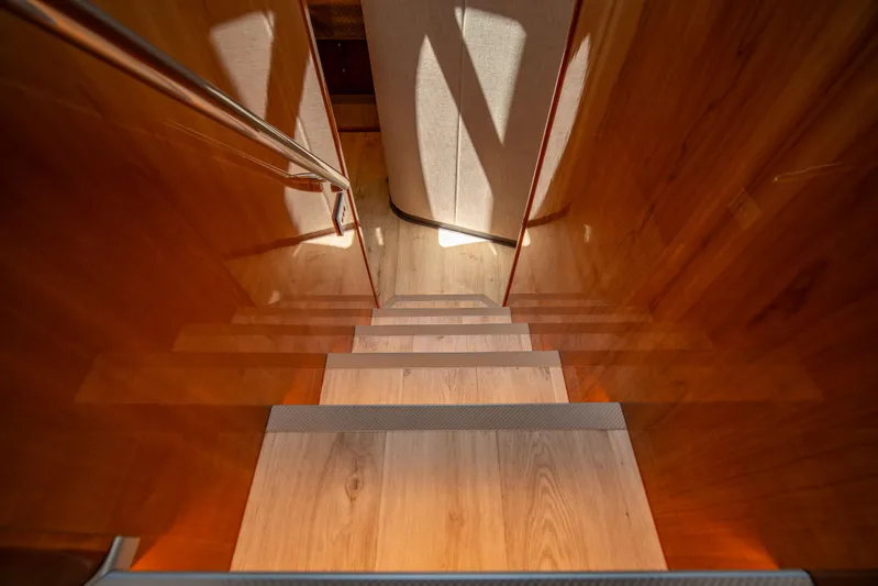  Yacht Photos Pics Wooden staircase inside 2020 Riviera 525 SUV yacht, featuring sleek design and warm lighting.