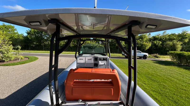  Yacht Photos Pics 2023 Fluid Watercraft M35 boat with orange seating and canopy, parked on a grassy area.